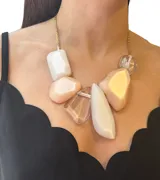 Collar con cadena dorada y dijes grandes de resina en tonos blanco, rosa y transparente.