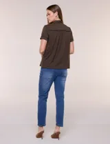Camisa de manga corta color marrón oscuro, con cuello camisero, alforzas verticales, detalles de puntilla calada y frunces bajo el busto. Cuenta con cierre frontal de botones.