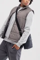 Chaleco puffer color gris topo, con cuello alto y cierre frontal.