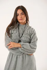 Vestido largo a rayas verticales en tonos verde y blanco, con cuello alto fruncido, mangas largas abullonadas y falda amplia. Presenta un diseño de nido de abeja con hilo elástico hasta la cintura.