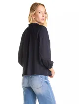 Blusa de gasa con plisado soleil, cuello a la base fruncido con escote en V regulable mediante lazos, y mangas largas abullonadas con puños sastreros.