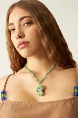 Collar de cuentas de piedra verde con dije de cerámica en forma de concha.