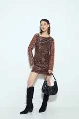 Vestido corto de manga larga, escote redondo y calce ajustado. Confeccionado en tejido liviano con estampado tipo damasco o paisley en tonos negro, marrón y dorado/plateado brillante.