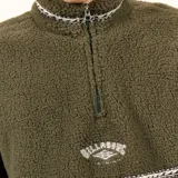 Buzo de polar tipo sherpa color verde oliva, con cuello alto y cierre frontal parcial. Presenta detalles de cinta tejida con diseño geométrico en el cuello, pecho y bolsillos laterales. Incluye logo de la marca bordado en el centro del pecho.
