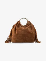 Cartera de mano confeccionada en gamuza color marrón, con diseño flexible y flecos decorativos en los laterales. Presenta un asa rígida circular de metal plateado.