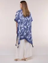 Kimono de gasa ligera con estampado floral en tonos de azul y blanco, silueta amplia, mangas cortas y detalle de borlas en el ruedo asimétrico.