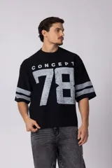 Remerón de corte oversize con cuello redondo y mangas cortas. Presenta un diseño estampado frontal con la palabra 'CONCEPT' y el número '78' en efecto desgastado, además de dos franjas horizontales en las mangas.