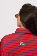 Camisa roja de manga larga con rayas verticales azul marino, bolsillos frontales con solapa y cierre de botones.
