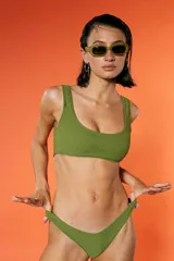 Top de bikini verde militar con textura arrugada, escote amplio y breteles fijos. Incluye bombacha vedetina con frente en V.