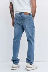 Pantalón de jean corte regular, color azul medio con efecto lavado, de tiro medio y cierre frontal con botón y cremallera.