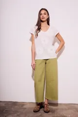 Remera de algodón color blanco con cuello en V y mangas cortas. Presenta un diseño con flores bordadas en relieve y detalles calados en el tejido.