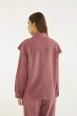 Camisa de denim color rosa viejo, con cuello clásico, volados grandes en el delantero, cierre frontal con botones y mangas largas con puños.