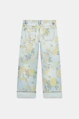 Jeans de tiro bajo y corte holgado, color celeste con estampado floral en tonos amarillos y verdes. Presenta diseño de cinco bolsillos, trabillas para cinturón y dobladillo con vuelta en los bajos. Cierre frontal con cremallera y botón metálico.