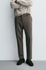 Pantalón de corte slim fit y color negro, confeccionado en tejido elástico. Cuenta con cintura elástica, trabillas, bolsillos frontales y cierre con cremallera y botón.
