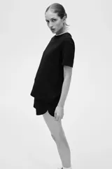 Remera de punto interlock pesado color negro, con cuello redondo ribeteado en canalé, mangas cortas y bajo recto.