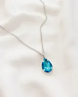 Collar plateado con dije de cristal en forma de lágrima color turquesa.