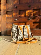 Cartera tipo tote bag con estampado animal print, doble asa de mano color cuero y correa larga desmontable y regulable.