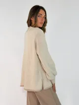 Sweater de tejido de punto en color azul marino, con cuello redondo, mangas largas con puños acanalados y ajuste holgado. Presenta un pequeño aplique decorativo en el ruedo.