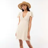Vestido corto de corte evasé, con estampado floral sutil en tonos rosados y verdes sobre base blanca. Presenta escote en V y mangas cortas tipo mariposa.