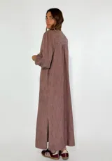 Vestido largo color beige con escote en V, mangas 3/4 abullonadas y corte holgado.