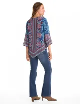 Blusa de gasa con estampado floral y geométrico en tonos azules, rojos y celestes. Presenta cuello a la base, mangas tres cuartos amplias y un corte asimétrico en el ruedo.