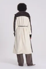 Tapado largo de piel sintética color gris topo, con cuello solapa, lazo de cuero sintético negro en la cintura y forro de tafeta con logo de la marca.
