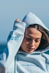 Hoodie celeste con capucha, cordones ajustables y bordado con la frase "Glassy Waves" en el pecho.