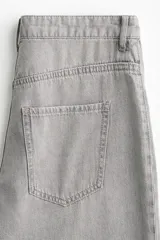 Jean de denim rígido color gris claro lavado, tiro superalto, pierna ancha y corte holgado. Presenta bolsillos parche grandes en la parte delantera y bolsillos parche en la parte trasera. El bajo es largo y sin dobladillo.