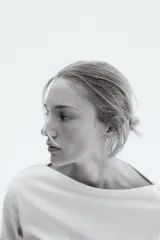 Top de manga larga color crema, confeccionado en punto suave de algodón, con escote bote y hombros caídos. Presenta un calce entallado en la cintura y mangas largas amplias.