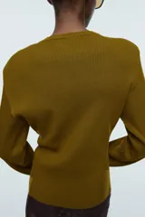Top de manga larga confeccionado en tejido de punto acanalado. Presenta un diseño ajustado con cuello redondo y hombreras integradas.