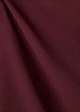 Vestido corto entallado de color bordó, con cuello barco y mangas largas. Presenta detalles de fruncidos laterales en la cintura.