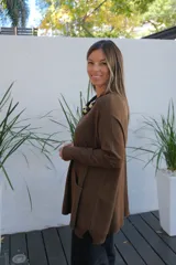 Sweater de tejido de punto en color chocolate, con corte holgado, cuello redondo y mangas largas. Presenta un diseño con bolsillos frontales integrados y terminaciones acanaladas en puños y ruedo.