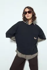 Remerón negro de manga corta, silueta amplia y efecto washed/dye. Presenta un bolsillo aplicado con bordado de perro salchicha.