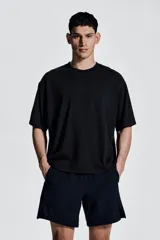 Remera deportiva negra de corte boxy, confeccionada en tejido funcional DryMove™ con efecto lavado. Tiene cuello redondo ribeteado acanalado y hombros caídos.