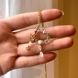 Collar dorado con cadena fina y dije con forma de corazón incompleto, decorado con piedras blancas y una mariposa dorada con detalles en blanco.