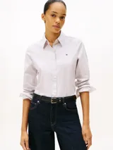 Camisa de popelina de algodón elástico a rayas verticales finas en tonos blanco y rosa. Tiene cuello inglés, puños y bajo camisero. Presenta logo de Tommy Hilfiger bordado en el pecho.