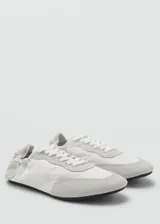 Sneaker Sofi de estilo minimalista en color gris claro, confeccionada en una combinación de piel vacuna y poliéster con detalles de gamuza en la puntera y el talón. Presenta cierre con cordones y un diseño fruncido en la parte trasera con elástico.