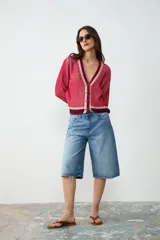 Cardigan de punto con escote en V y cierre frontal de botones. Diseño rayado en tonos rojo, rosado y azul marino, de manga larga.