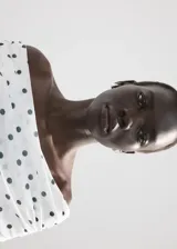 Vestido midi entallado de color blanco con estampado de lunares negros, escote palabra de honor con solapa drapeada y manga larga.