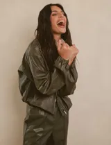 Chaqueta bomber de eco cuero color verde oliva, con cuello tipo solapa, cierre frontal metálico, bolsillos laterales y puños elásticos.