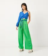 Pantalón de lino verde, modelo palazzo, con cintura alta, pliegues frontales y un cinturón bordado en tonos de verde y azul.