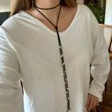 Corbatín negro de tiento largo con dijes de estrellas plateadas.