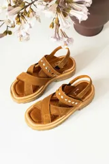 Sandalias de cuero marrón con textura de cocodrilo, diseño de tiras cruzadas con tachas metálicas plateadas y suela track negra de plataforma.