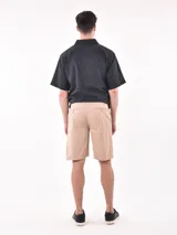 Bermuda de gabardina color beige, con corte recto, bolsillos laterales y cierre frontal.