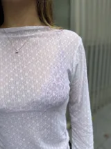 Polera de manga larga confeccionada en tela de gasa elastizada con encaje delicado y bordado a tono. Presenta un diseño ajustado al cuerpo con cuello redondo.