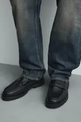 Mocasín de vestir negro con capellada lisa, detalle de antifaz en el empeine y suela track robusta.