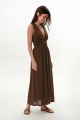 Vestido largo negro con brillo sutil, escote profundo en V y cintura marcada con frunces. Diseño sin mangas y falda amplia.