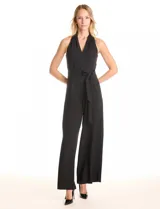 Enterito largo negro de crepe, con escote en V cruzado, sin mangas y lazo de ajuste en la cintura. Presenta bolsillos verticales en la parte delantera y una abertura en forma de gota con broches de gancho y cierre invisible en la espalda.