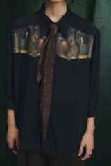 Camisa negra de manga larga con canesú frontal estampado con motivos artísticos de bodegón. Incluye una corbata fina integrada del mismo tono.
