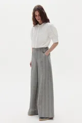 Camisa blanca de algodón con cuello mao, botonera oculta, mangas cortas estilo raglán con cortes estructurados y un bolsillo frontal con cierre.